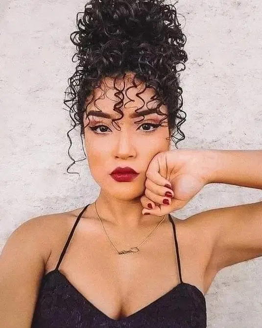 High Curly Bun with Wispy Bangs Hairstyle